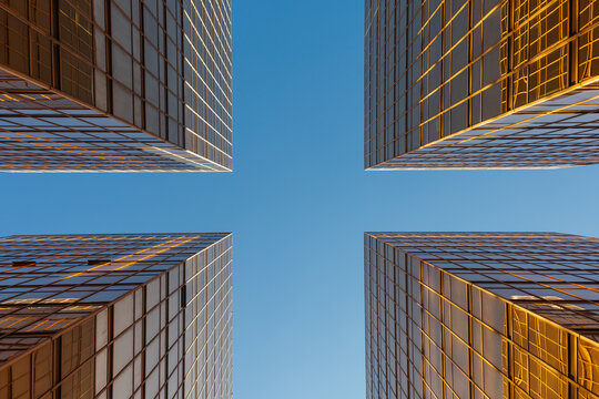 Upward view of modern glass buildings reflecting sunlight against blue