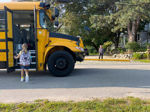 Young Girl board School bus on first day 
