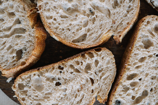 Sliced rustic bread on wooden surface, close-up view.