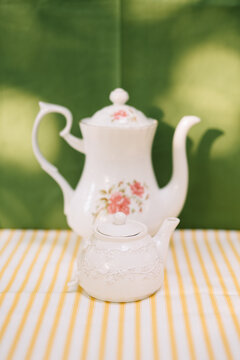 Two teapots with floral patterns on a green background