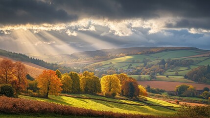 Obraz premium Early morning sunlight piercing through clouds over a vibrant autumn landscape of rolling hills.
