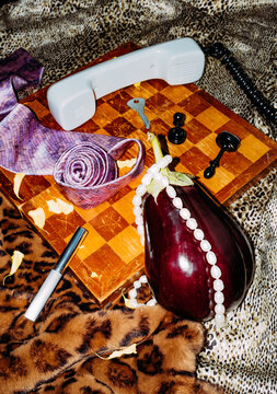 Creative flat lay with eggplant, chessboard, and miscellaneous items.