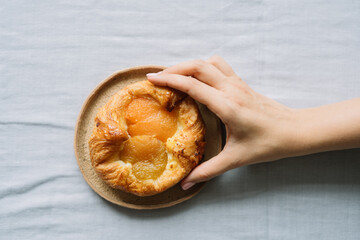 Hand reaching for a delicious fruit danish on plate