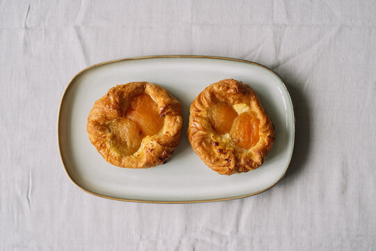 Two apricot pastries on a white rectangular plate.