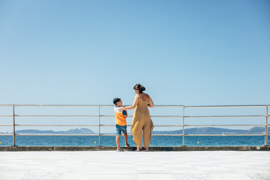 Mother and son enjoying sunny day by the ocean on a boardwalk