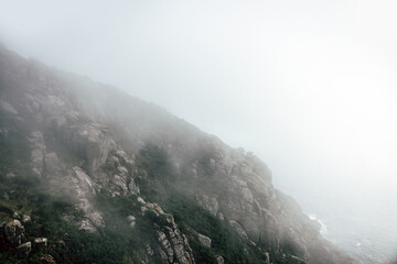 Foggy cliffside by the sea with rocks in Finisterre, Galicia, Spain