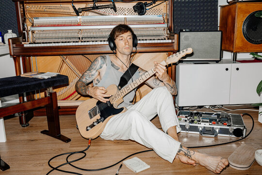 The musician plays the guitar and records music at home