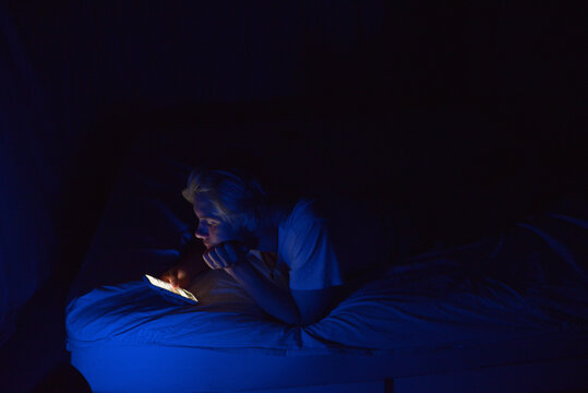 A young man doom-scrolling at night 