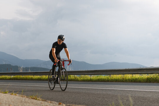 Man on road bike in morning sun in Austrian alps.