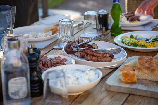 Family dinner table with barbecued meat and salads. 