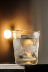Refreshing Cocktail with Large Ice on a Table and Lamp