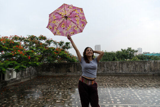 Young woman enjoying rainfall holding umbrella