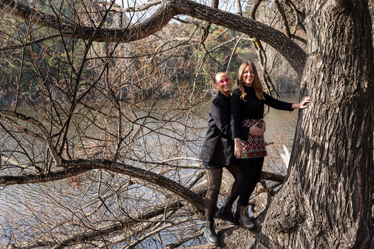 Two friends enjoying nature on a tree by a river bank in Australia