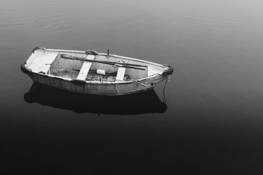 Old wooden boat floating on calm water in black and white photography