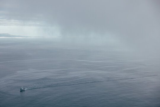 Small boat navigating through misty waters under overcast sky