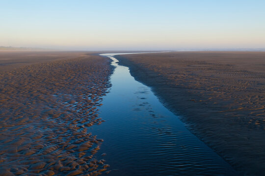 Tide pools on expansive beach at dusk