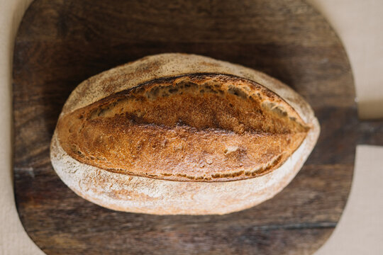 Whole artisan bread loaf on rustic wooden cutting board