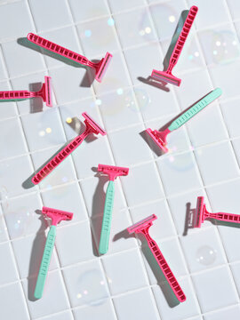 vibrant razors arrangement with soap bubbles on a white tiled su