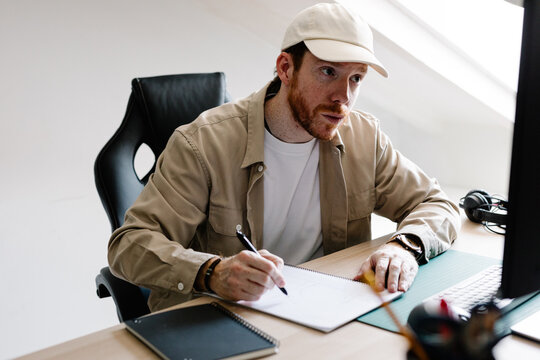 A freelancer makes handwritten notes during a virtual meeting