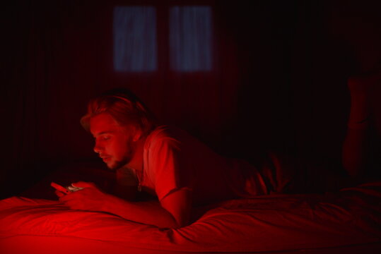 A young man doom-scrolling at night 