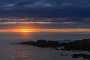 Coastal sunset over rocky shore with dramatic clouds