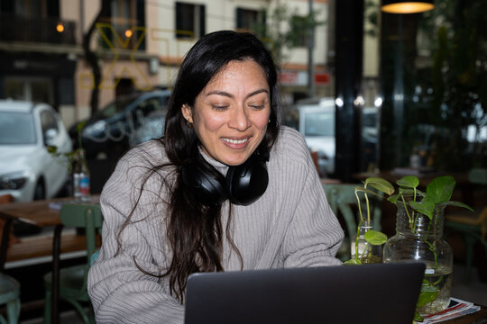 A hispanic businesswoman smiling while using a computer in a cafe