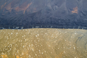 Brown, floating foam on surface of tide pool water