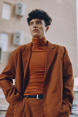 Stylish man in a brown suit and turtleneck, posing confidently outdoors Urban backdrop with a...