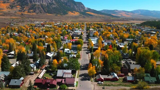 Main street Mount Crested Butte mountain town ski resort Kebler Ohio Pass aerial drone Colorado morning vibrant Aspen Trees fall autumn peak colors Gunnison National forest sunny blue sky forward pan