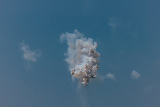Formation of white smoke plume from fireworks in clear blue sky