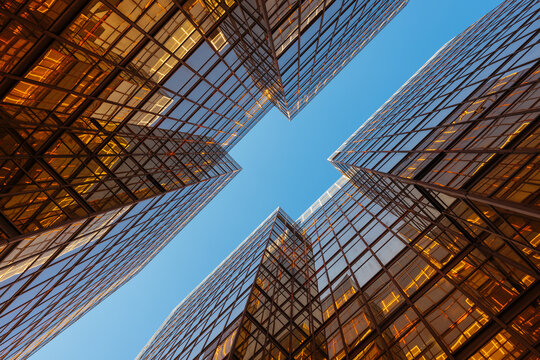 Symmetrical Glass Buildings Reflecting Golden Light Against Blue Sky - Powered by Adobe