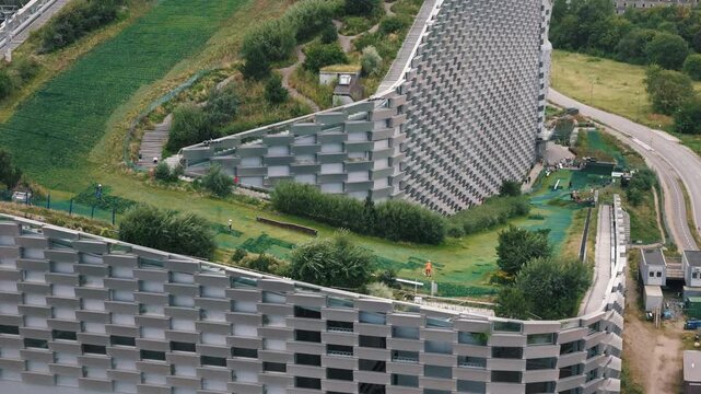 Close tracking of family skiing on Copenhill with view of energy plant architecture, Copenhagen