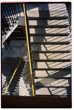 Spiral staircase with shadows and yellow railing in a modern building 