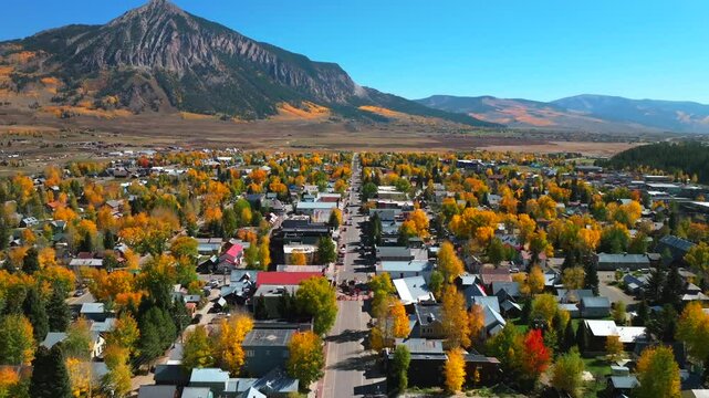 Main street Mount Crested Butte mountain town ski resort Kebler Ohio Pass aerial drone Colorado morning vibrant Aspen Trees fall autumn peak colors Gunnison National forest sunny blue sky forward