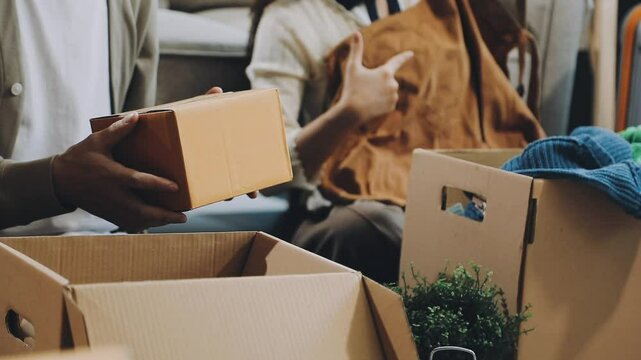 Young Asian couple relocating to a new house, joyfully packing and unpacking belongings. Expertise in moving, packing, togetherness, and creating a new home together.