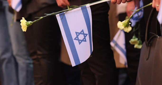 People hold the Israeli flag and flowers during a ceremony commemorating the October 2023 attacks on Israel.
