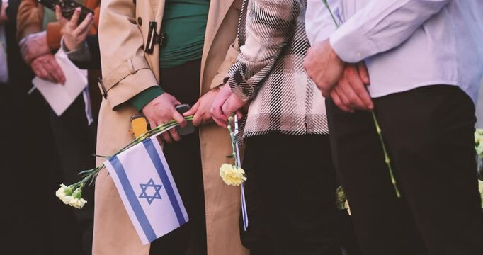 People hold the Israeli flag and flowers during a ceremony commemorating the October 2023 attacks on Israel.