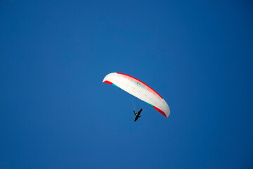 A man with a paraglider in front of a blue sky.