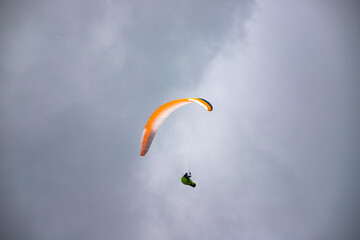 A man with a paraglider in front of a blue sky.