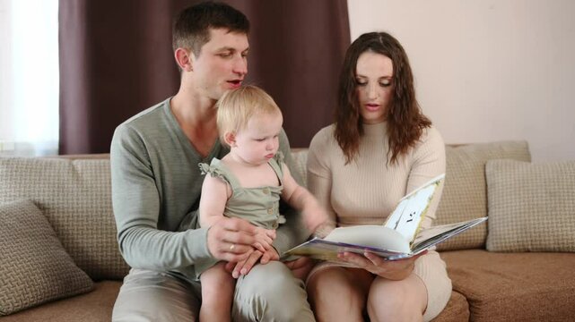 Parents and toddler spend time together, reading book of fairy tales while sitting on couch at home. Child does not want to listen attentively to story, constantly turning pages of book. Naughty child