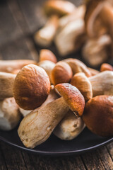 Fresh boletus mushrooms on plate on wooden table.