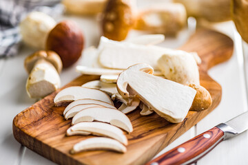 Fresh boletus mushrooms on cutting board on white table.