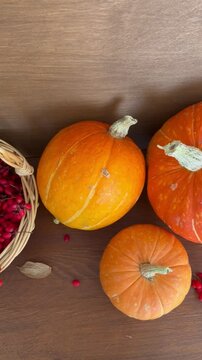 Vertical video of autumn rustic still life with basket of red barberries and ripe pumpkins on wooden table. Harvest time. Beautiful composition for autumn holidays and Thanksgiving