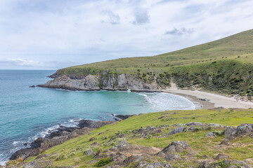 Fototapeta premium Beautiful Blowhole Beach, an idyllic cove between two steep sided headlands with aquamarine sea under an overcast sky in Deep Creek Conservation Park on the Fleurieu Peninsula in South Australia.