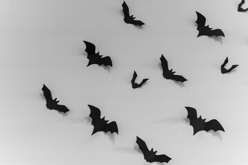 Black paper bats are scattered across a white wall, creating a spooky and whimsical Halloween decoration