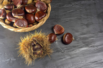 Chestnuts and autumn leaves on black background