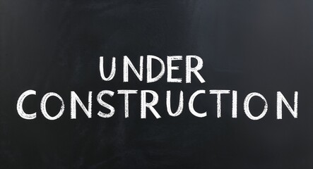 Obraz premium under construction text lettering on blackboard chalkboard background