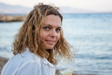 Portrait of a beautiful blonde woman with blue eyes by the sea