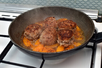 Cutlets are fried in a frying pan. Steam is coming from the cutlets. View from above.