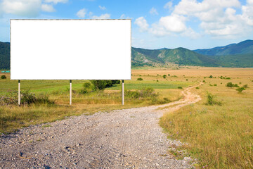 EMPTY ADVERTISING BILLBOARD IN A RURAL LANDSCAPE with a curved country road - Concept with...